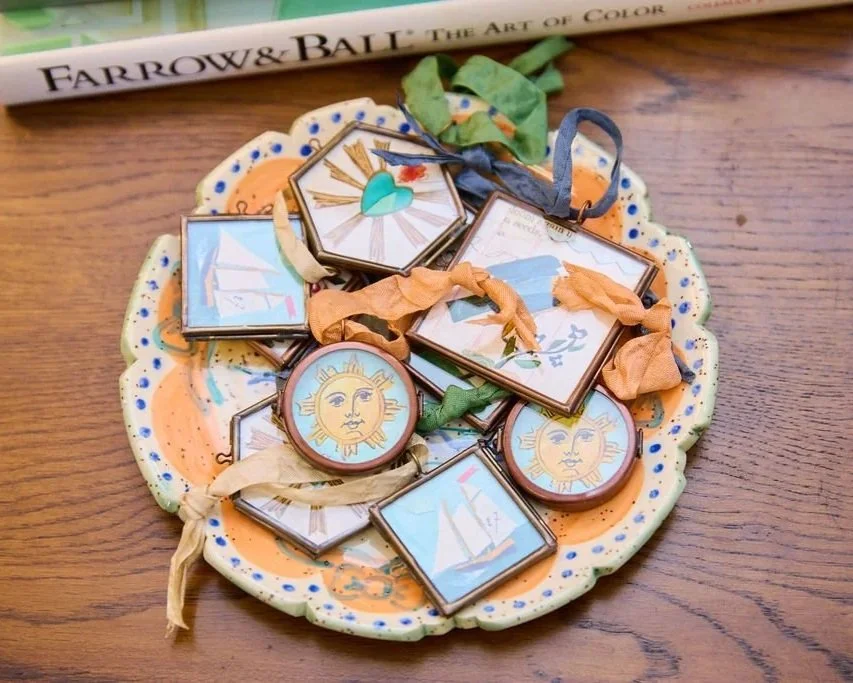 Vintage sun and sailboat ornaments with ribbons arranged on a colorful scalloped ceramic plate