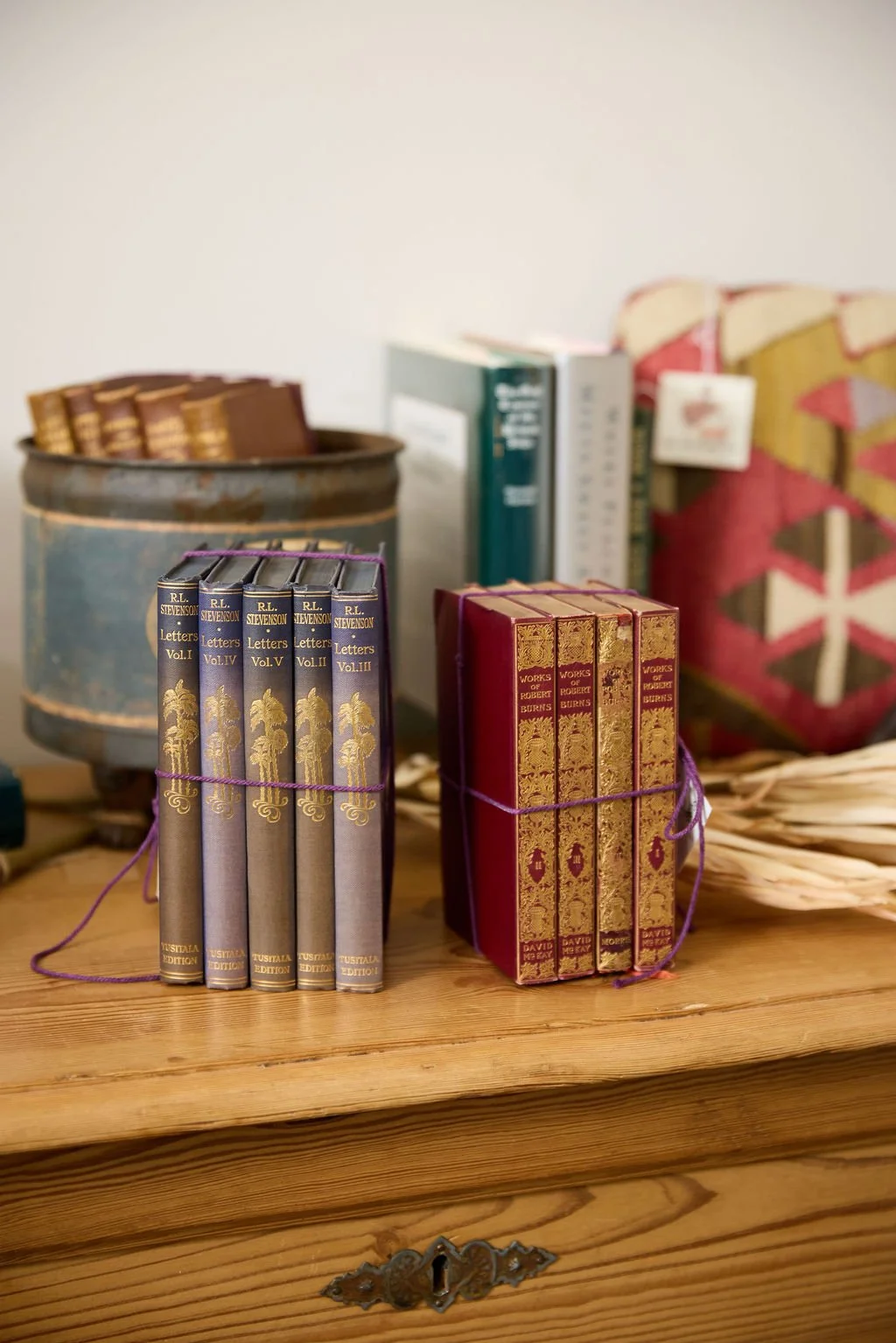 Vintage hardcover collections of R.L. Stevenson letters and Robert Burns works displayed on a wooden chest.