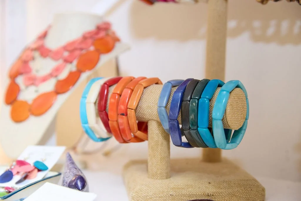 Colorful handmade bracelets displayed on a fabric-covered jewelry stand.