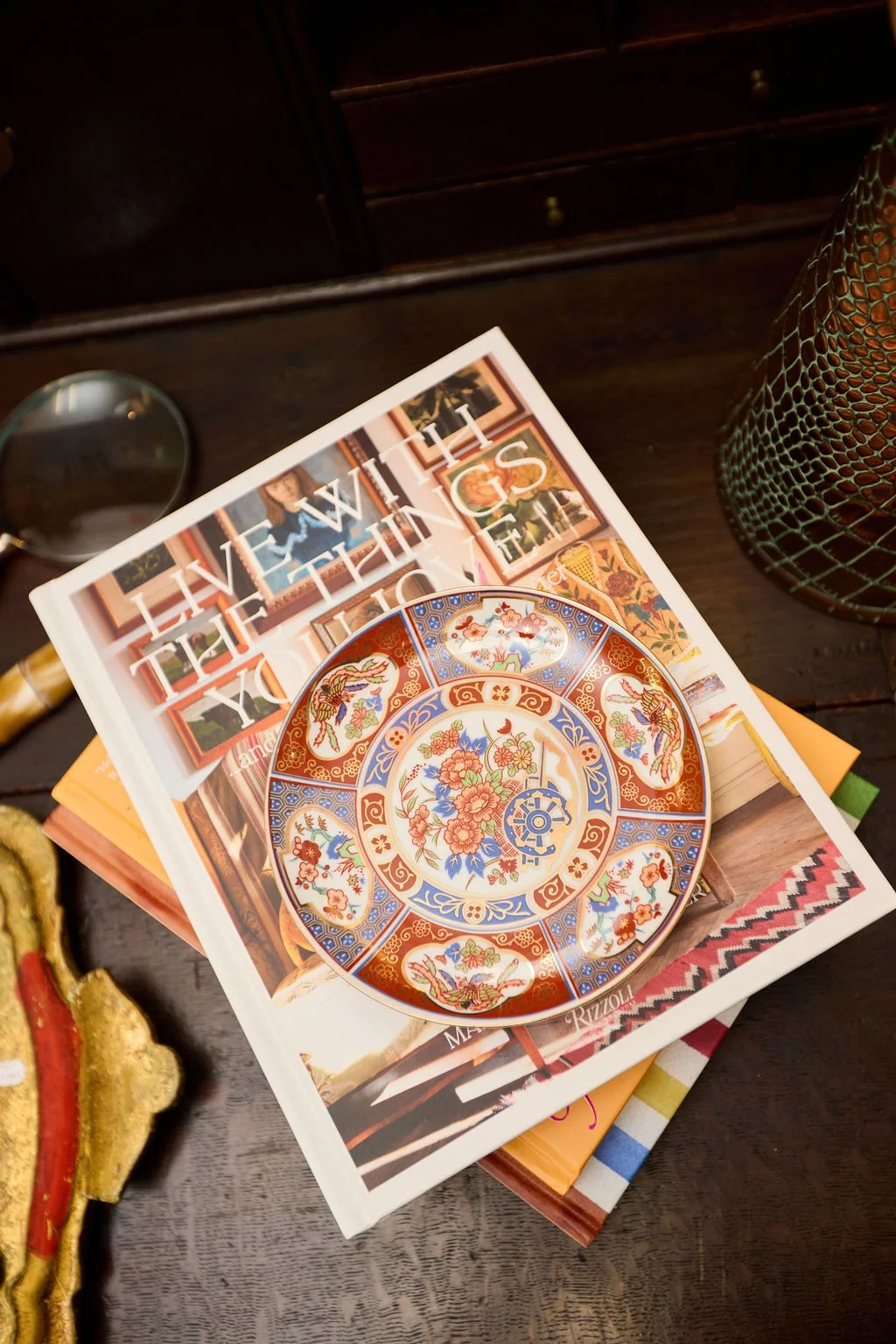 Ornate floral bowl on a stack of design books atop a dark wooden table