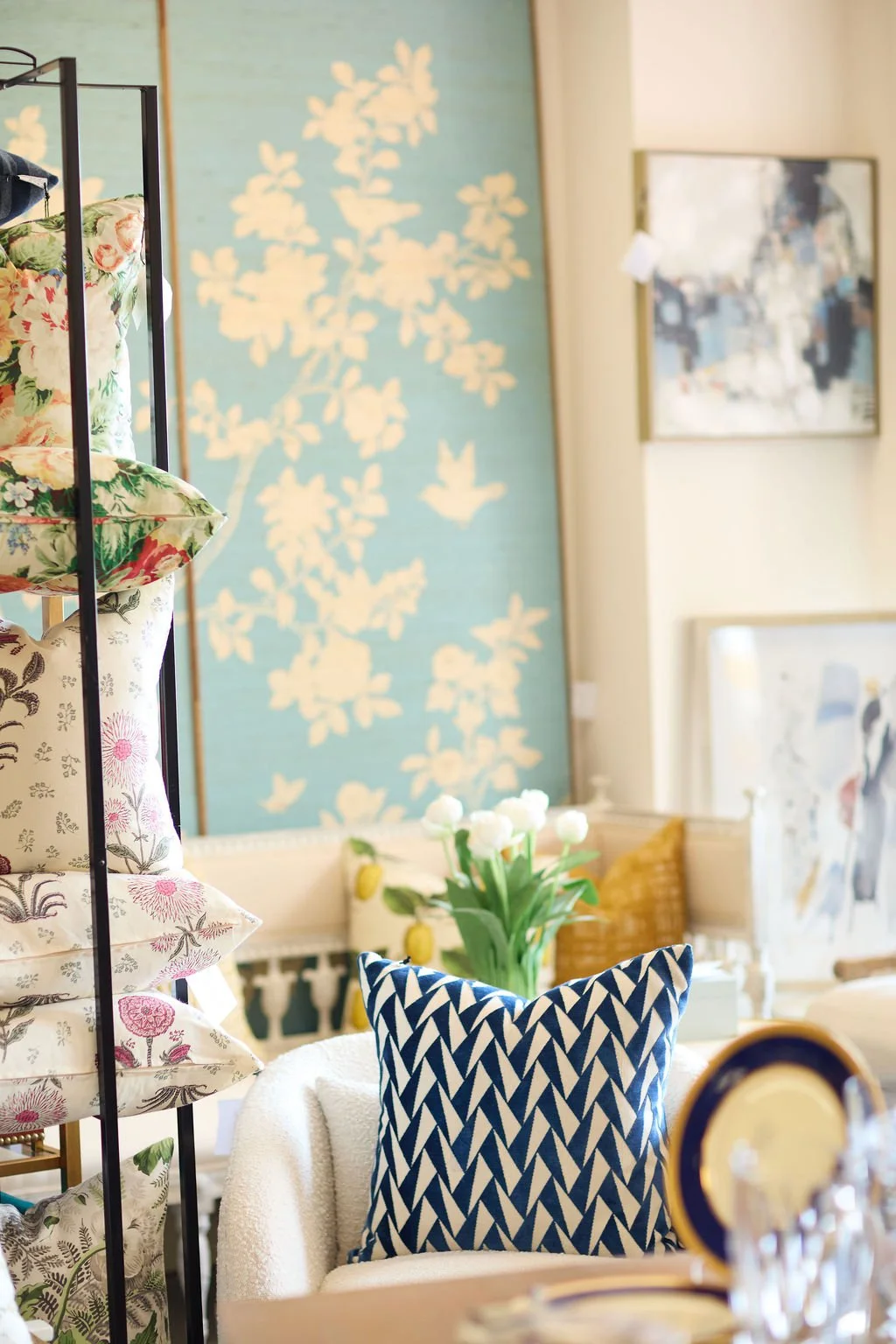 Eclectic living room with floral armchair, blue geometric throw pillow, botanical artwork, and fresh flowers
