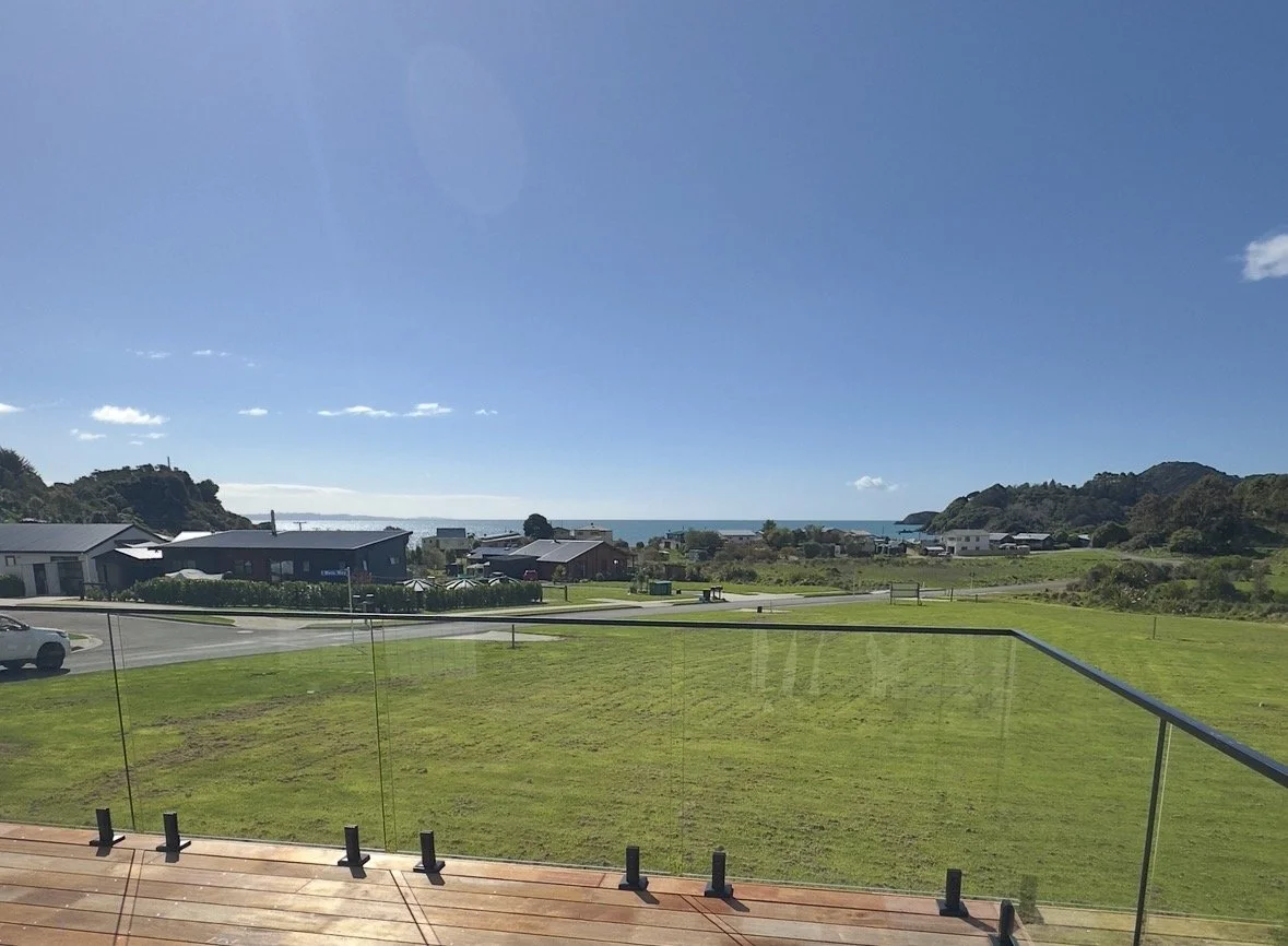 Coastal residential neighborhood and grassy field overlooking the ocean on a sunny day