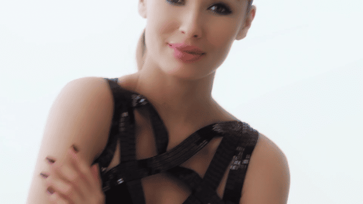 Portrait of a smiling woman wearing a black strappy top against a light background