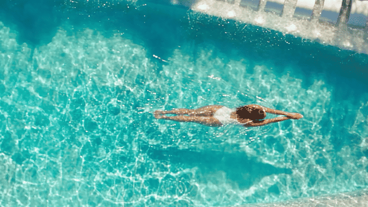 A swimmer glides underwater in a bright blue swimming pool.