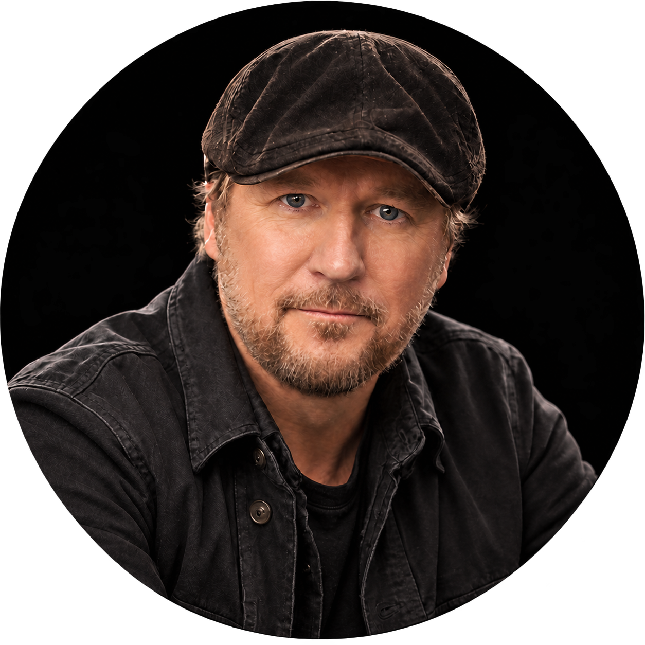 Portrait of a bearded man wearing a black leather cap and jacket against a black background
