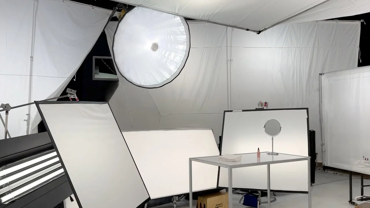 Professional photography studio with white light tents, reflectors, softbox lighting, and a makeup table