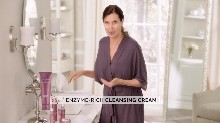 Woman presenting Dr. Dennis Gross enzyme-rich cleansing cream in a bright bathroom
