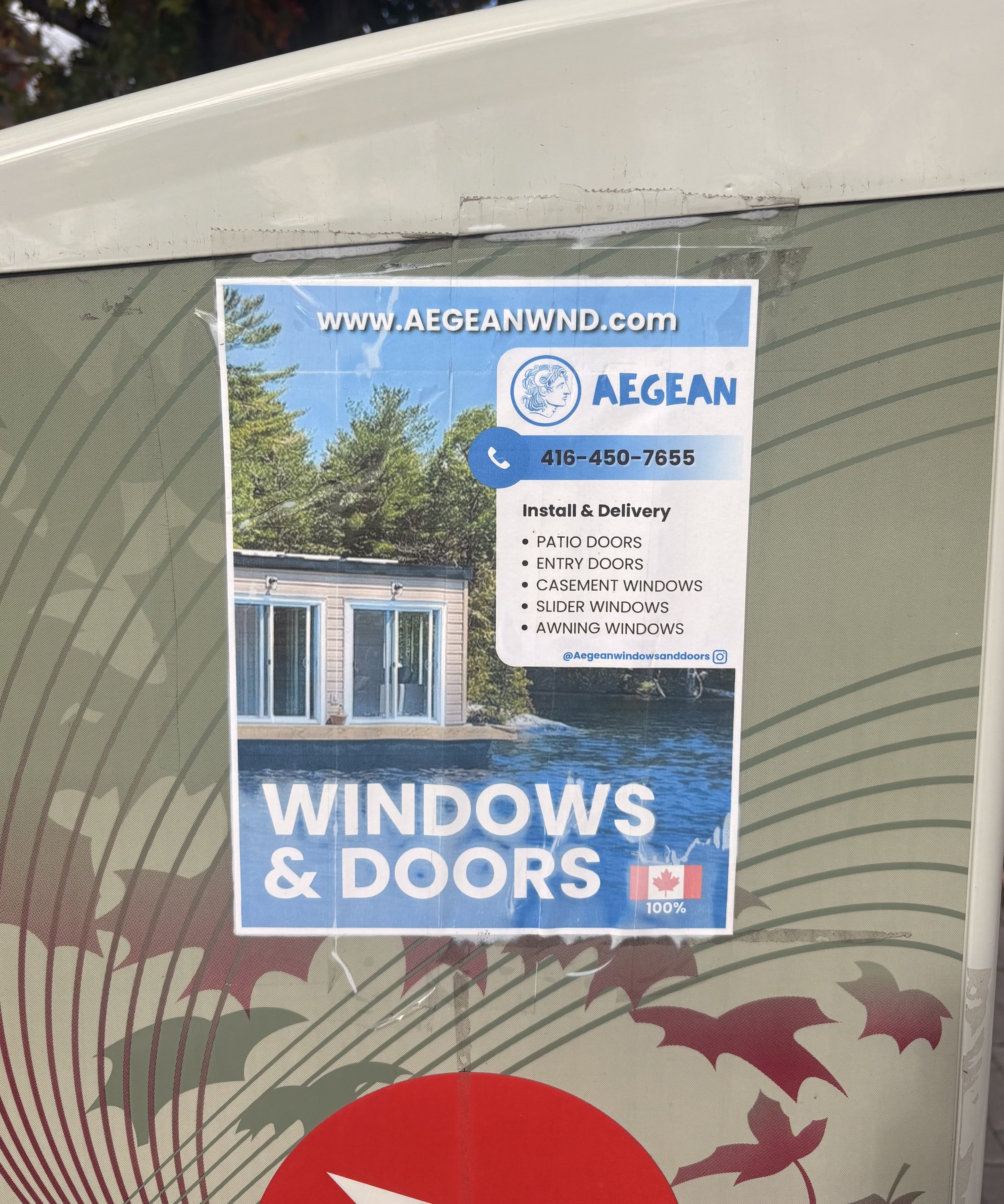 Aegean Windows & Doors advertisement on a patterned window covering, promoting installation and delivery of patio doors, entry doors, and windows.