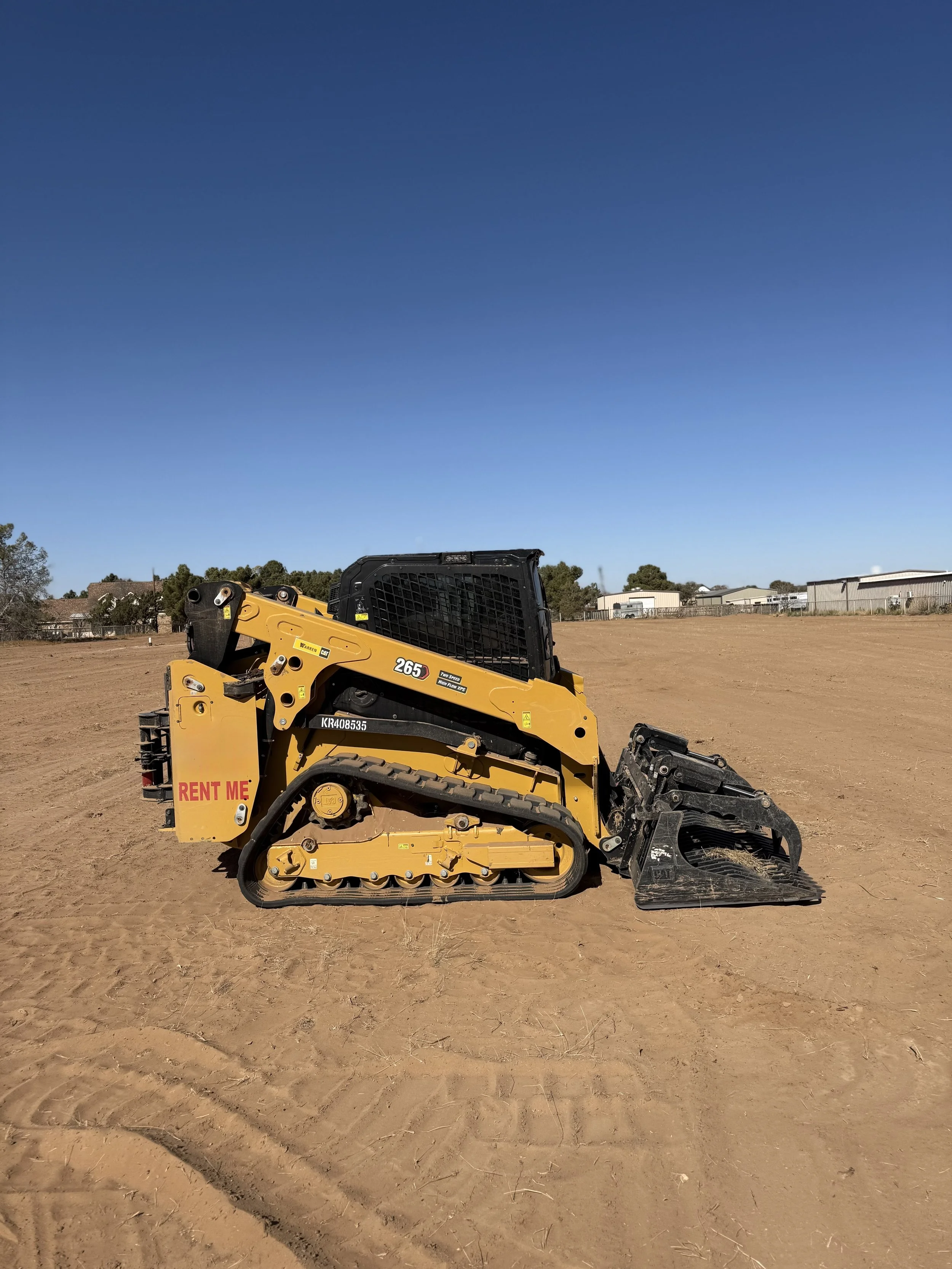 Cat 265 tracked skid steer loader with a grapple bucket attachment on a dirt construction site