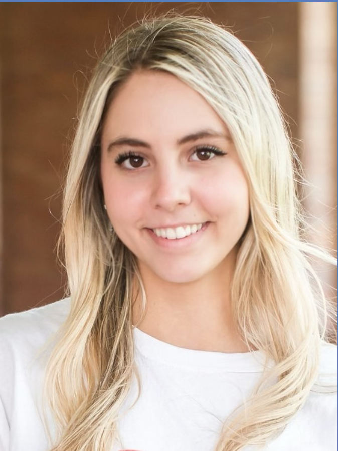 Smiling blonde woman with long wavy hair wearing a white shirt