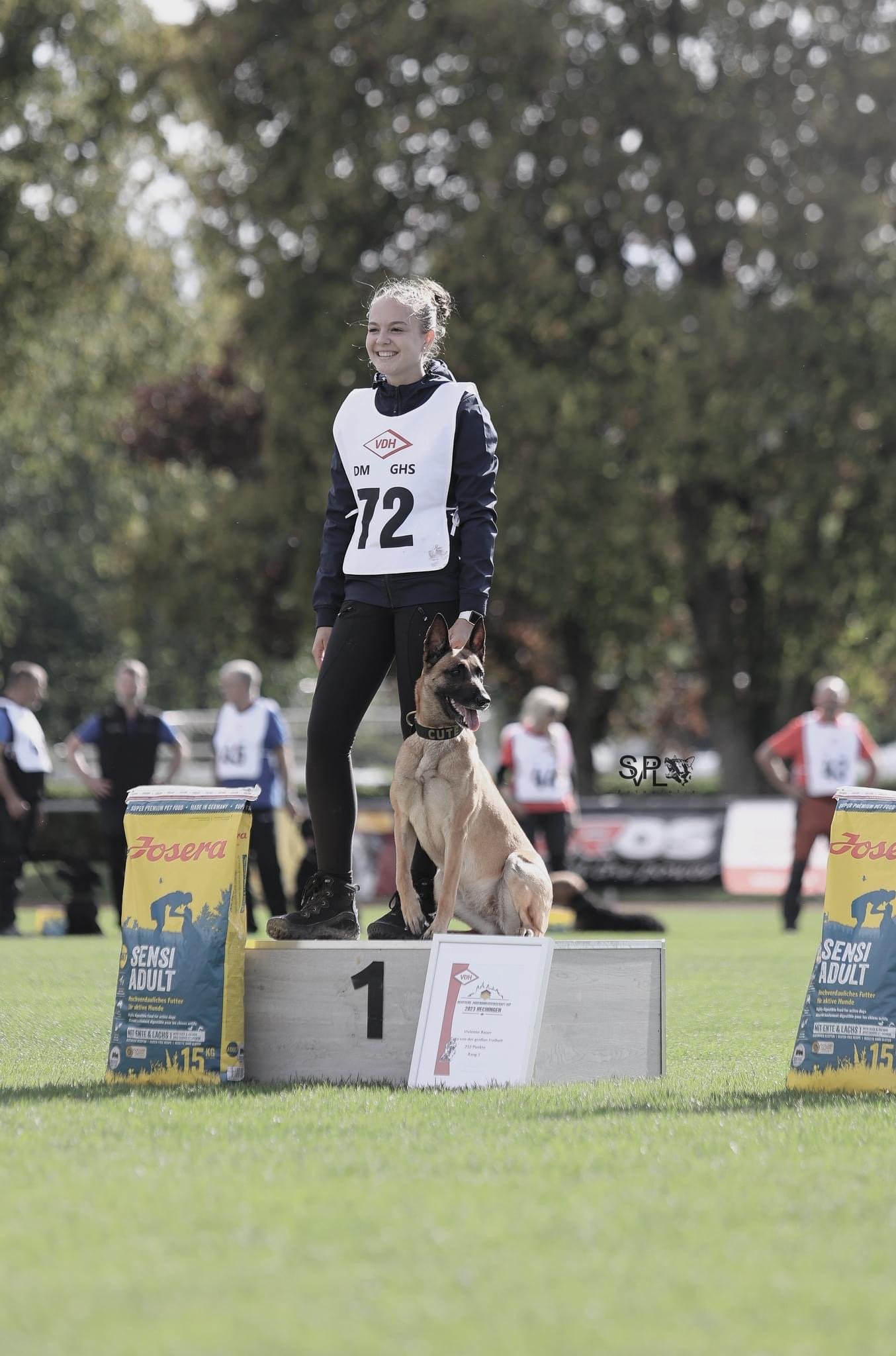 Hundetrainerin Vivienne von ViBaDog mit ihrem Malinois auf dem Siegerpodest eines Hundesport-Wettkampfs.