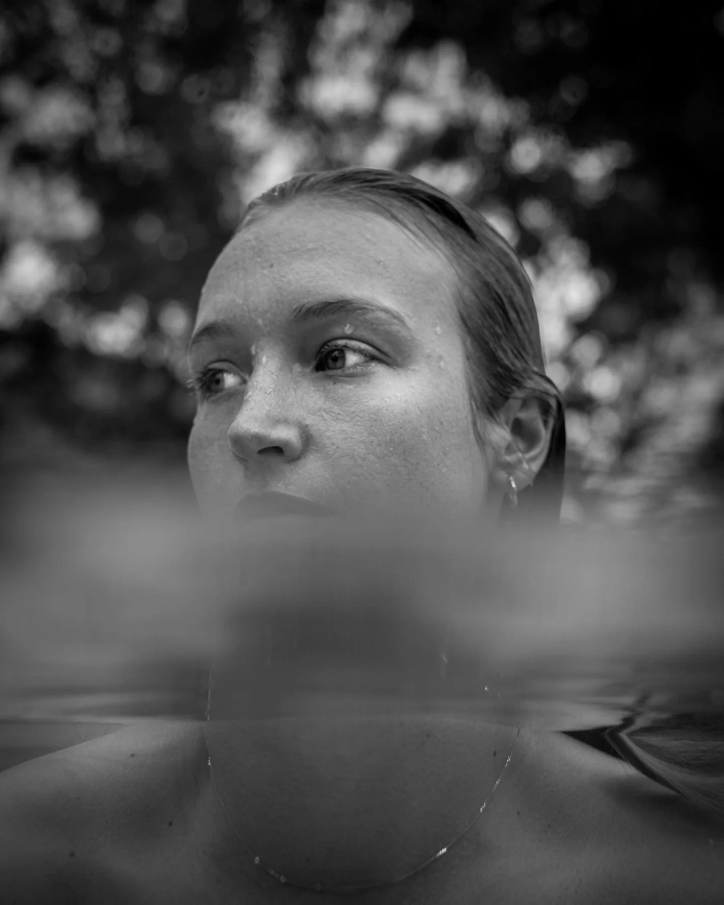 Black-and-white close-up portrait of a woman outdoors, partially submerged in water