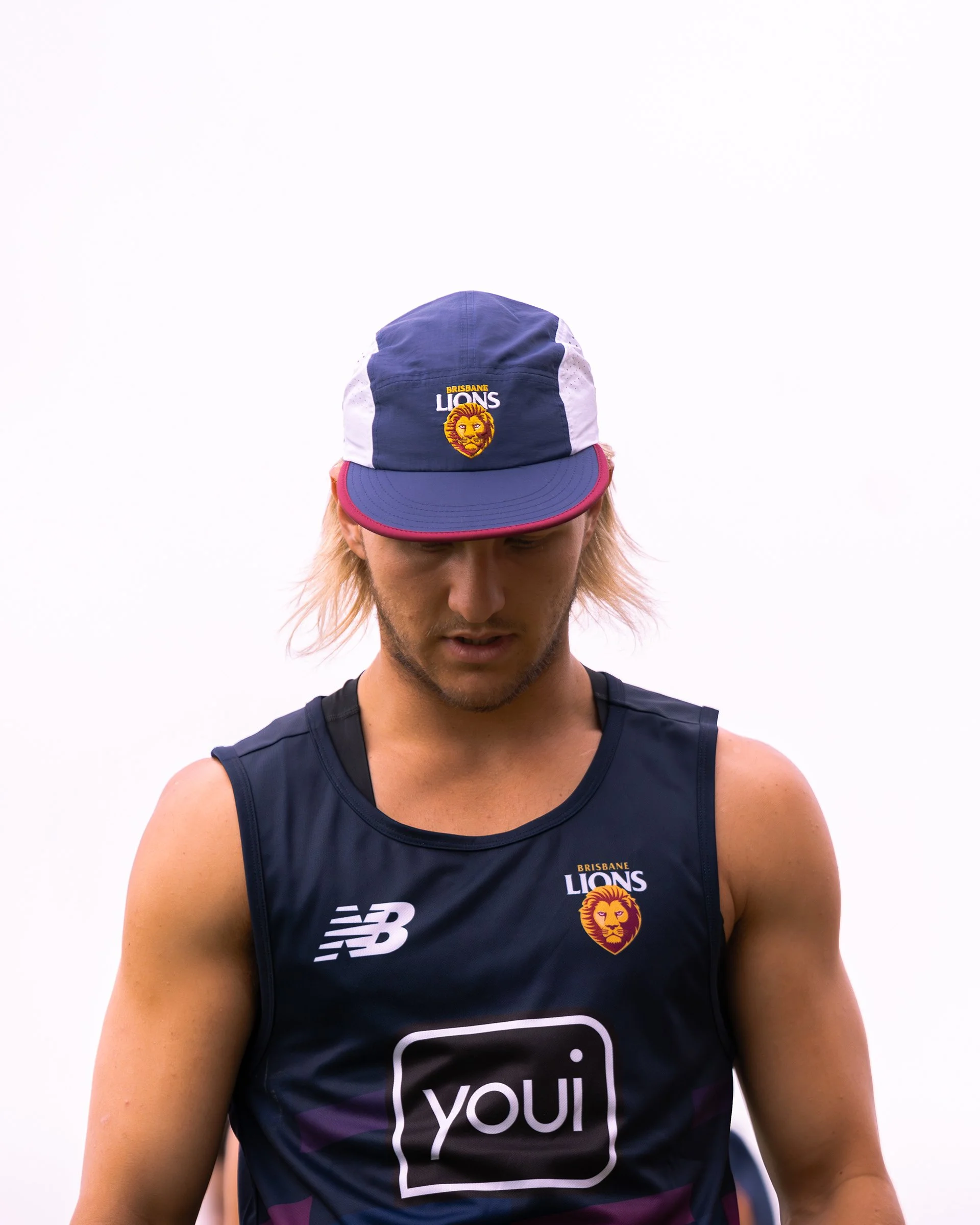 Brisbane Lions athlete wearing a navy New Balance jersey and matching lion-logo cap