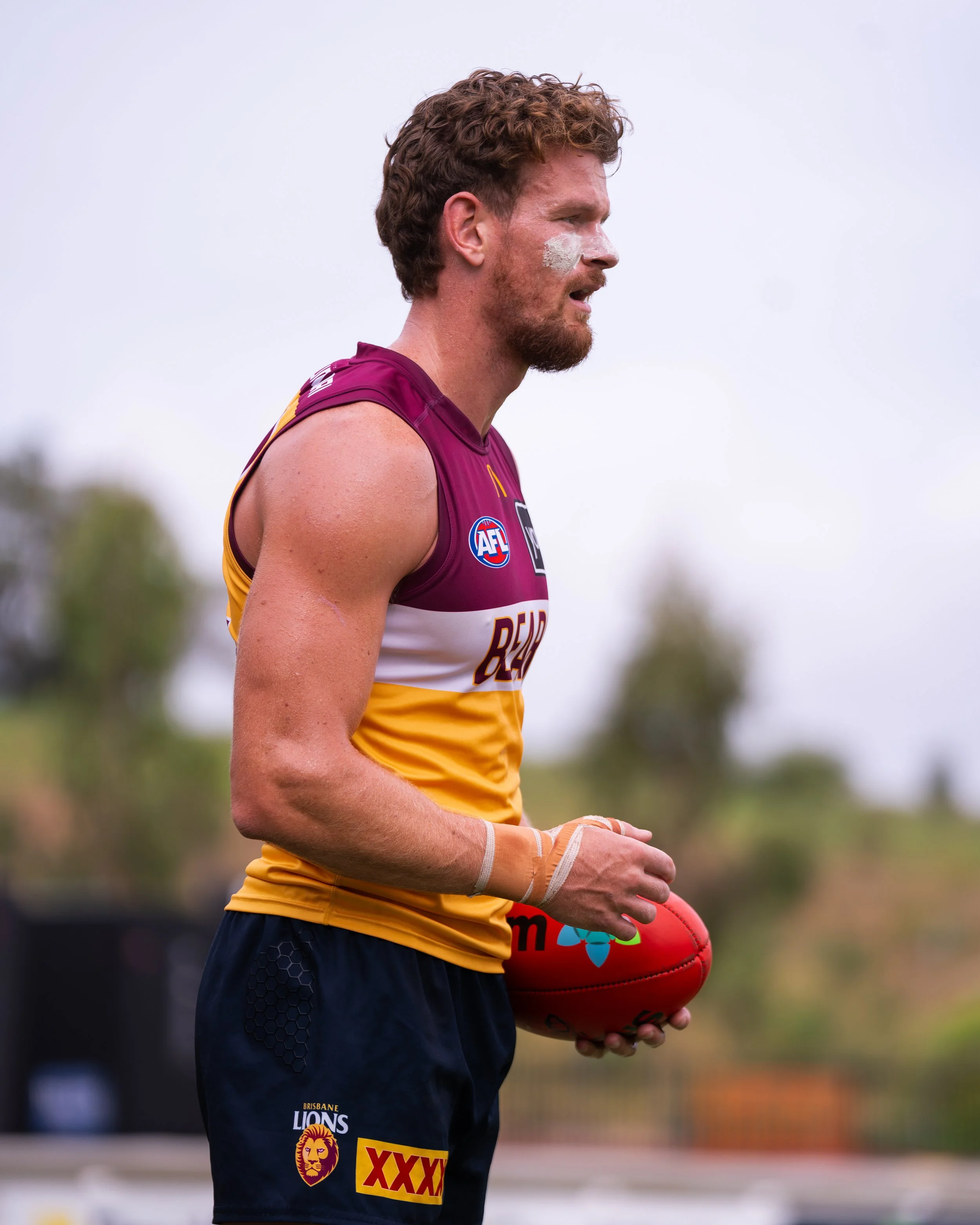 Brisbane Lions Australian rules football player holding a red football during training