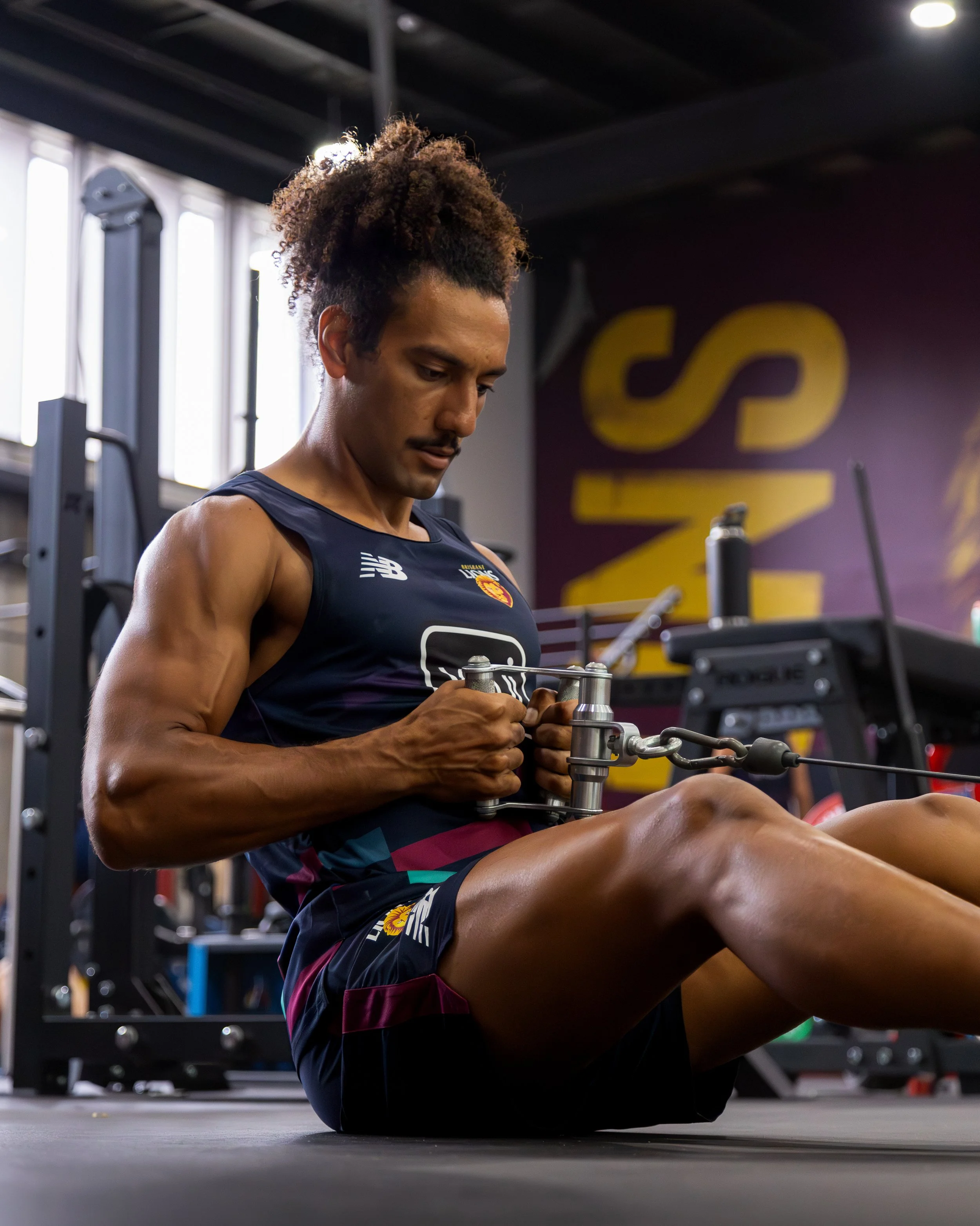 Athlete performing a seated cable row in a gym while wearing a New Balance training shirt