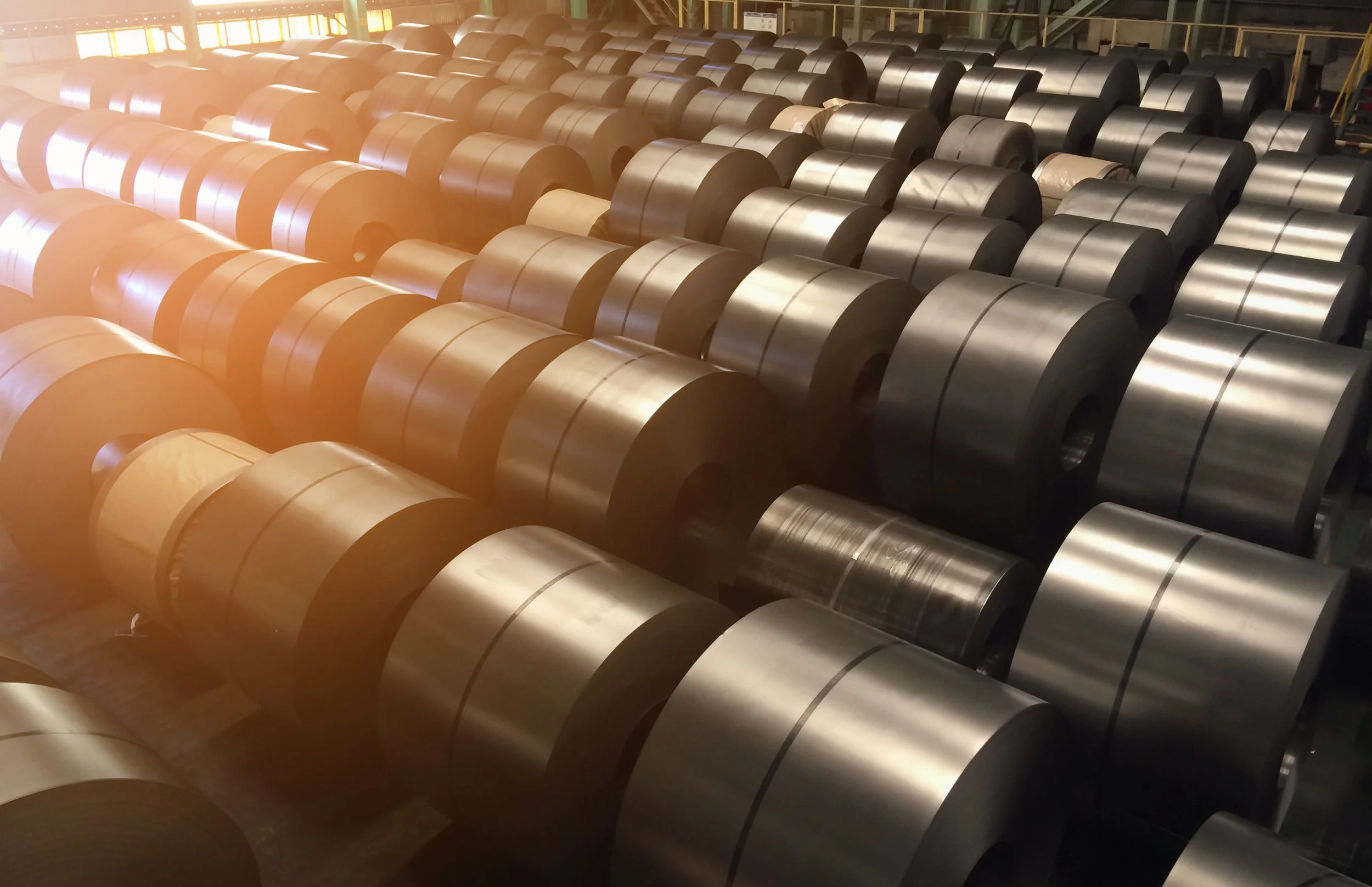 Rows of coiled metal sheets stored in an industrial warehouse