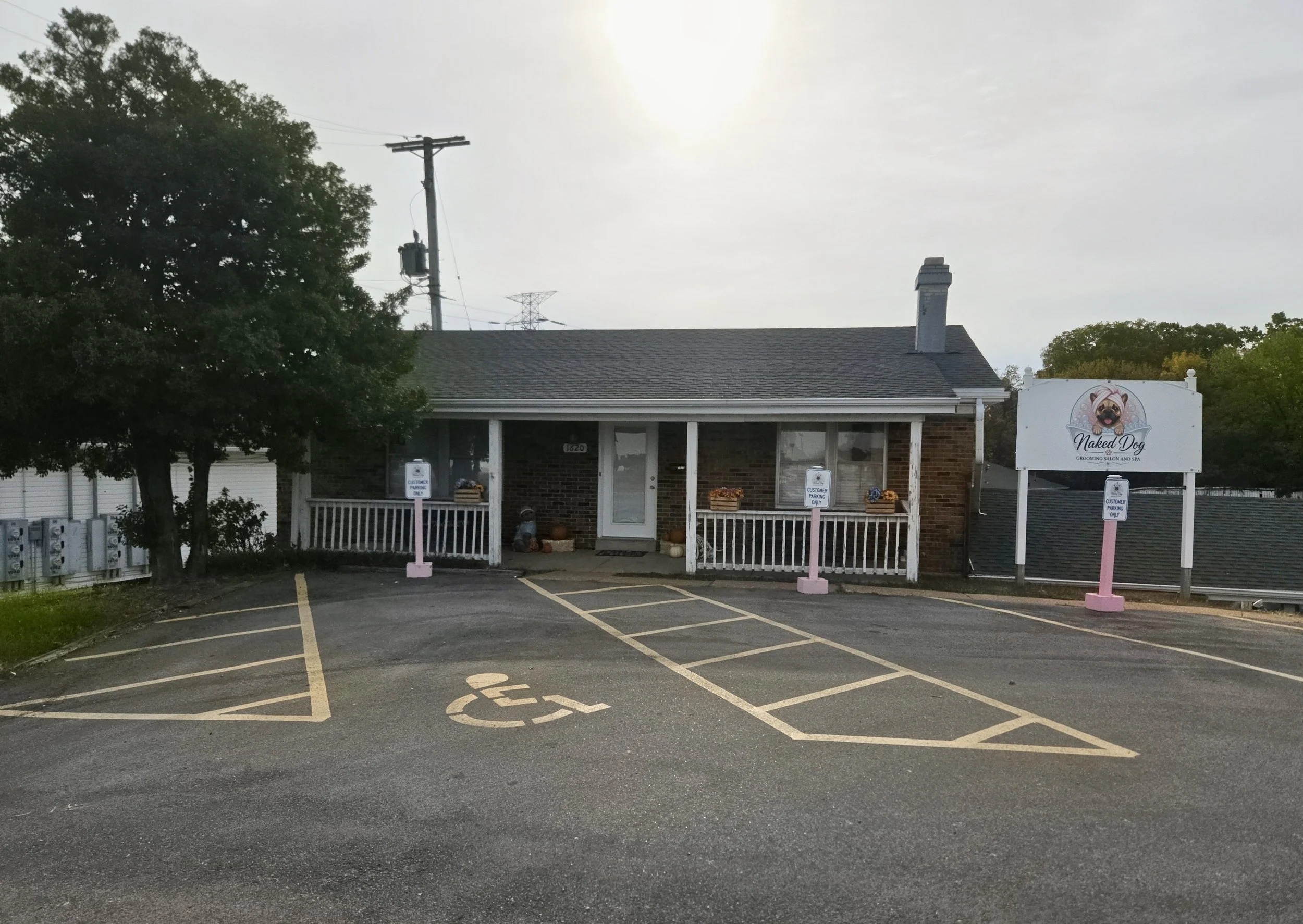 Exterior of Naked Dog grooming salon and spa with a pug sign, covered porch, and accessible parking spaces.