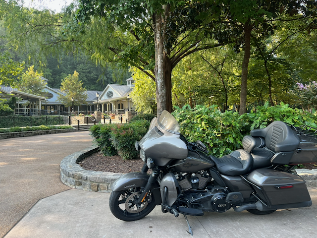 Gray touring motorcycle parked outside a landscaped building surrounded by trees