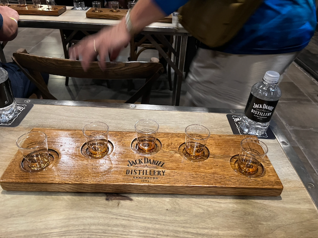 Jack Daniel’s Distillery whiskey tasting flight with five glasses on a wooden serving board.