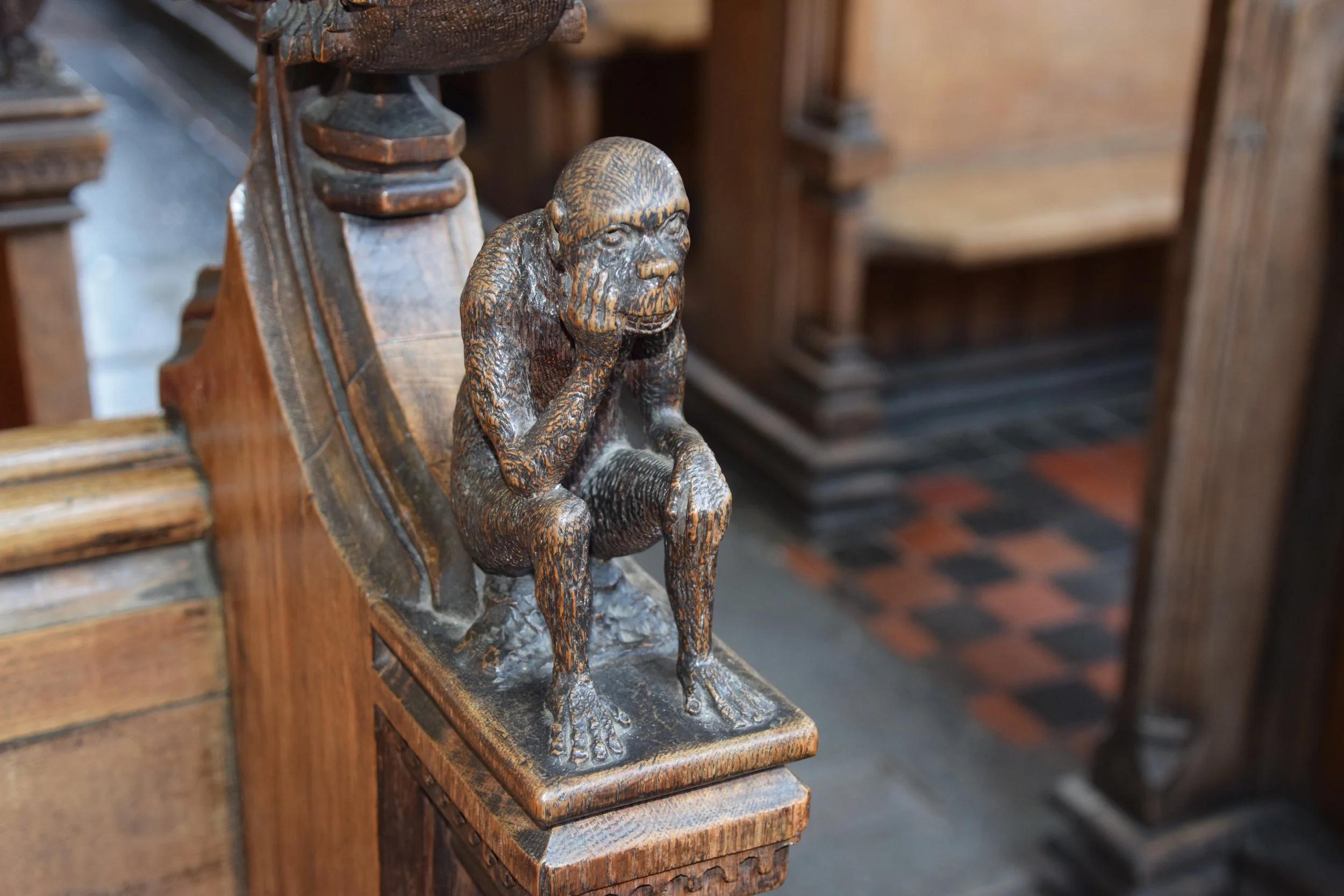 Antique carved wooden monkey statue on a bookshelf in a historic interior
