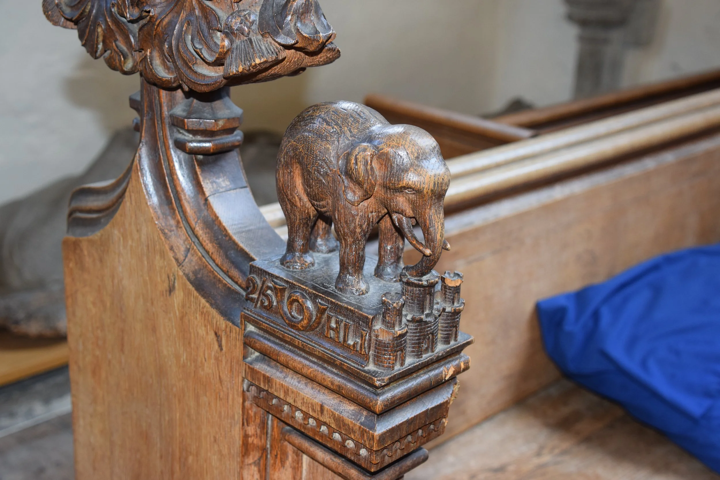 Carved wooden elephant sculpture on an ornate pedestal beside piano strings