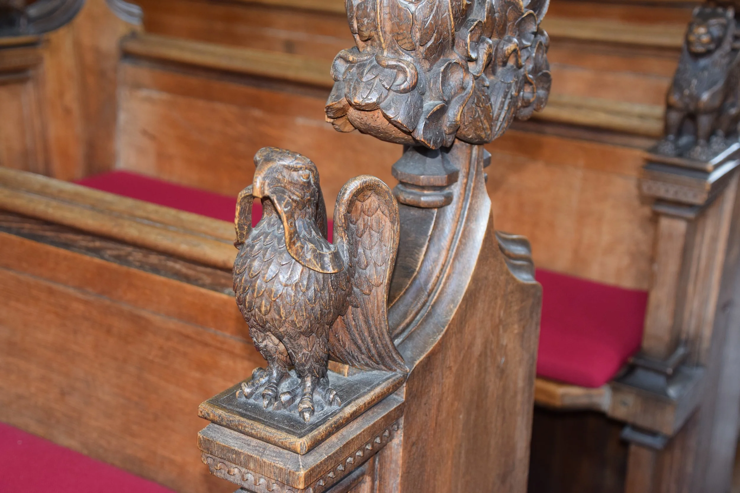 Ornate carved wooden eagle finial on a historic church pew