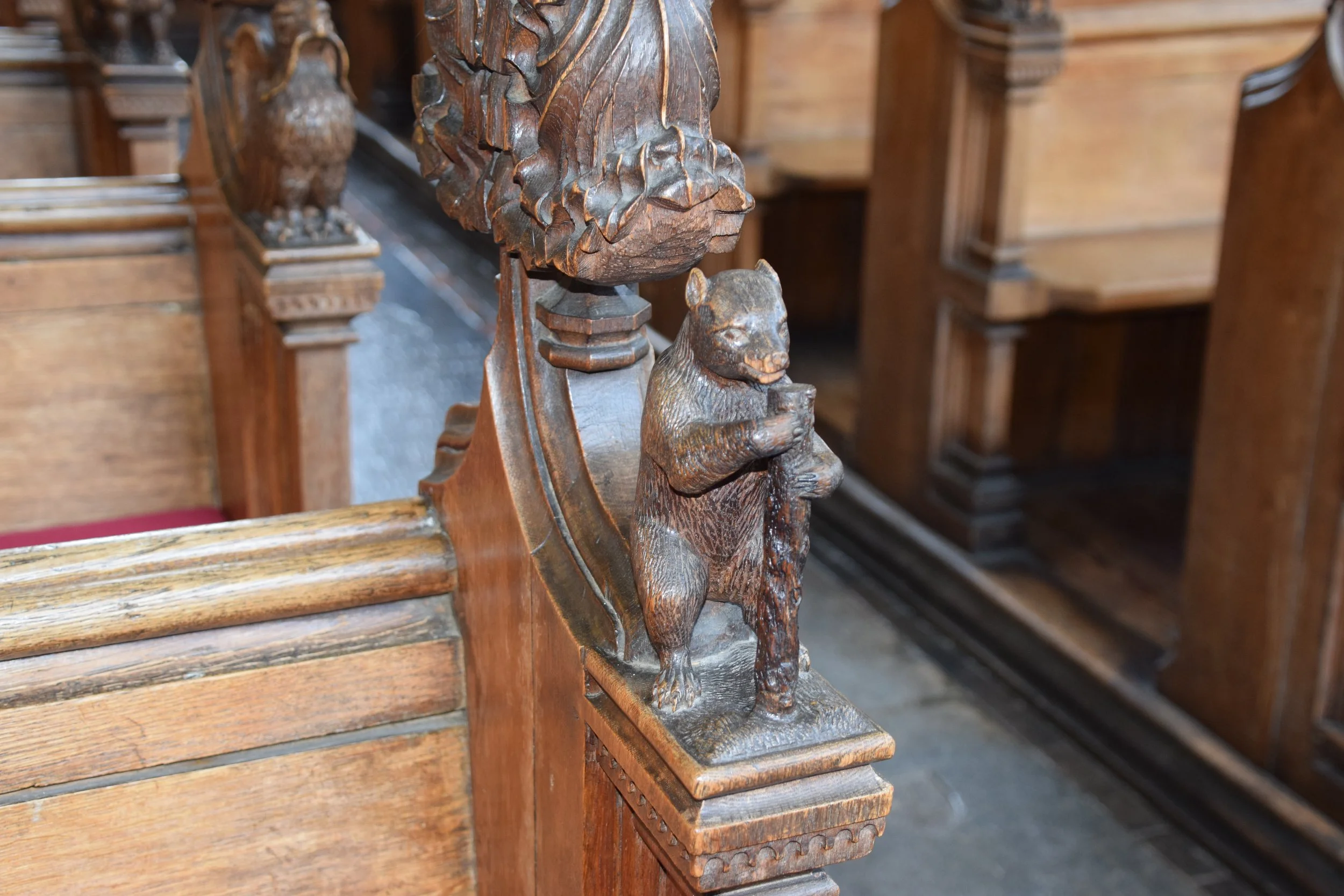 Intricately carved wooden monkey figure on a historic church pew