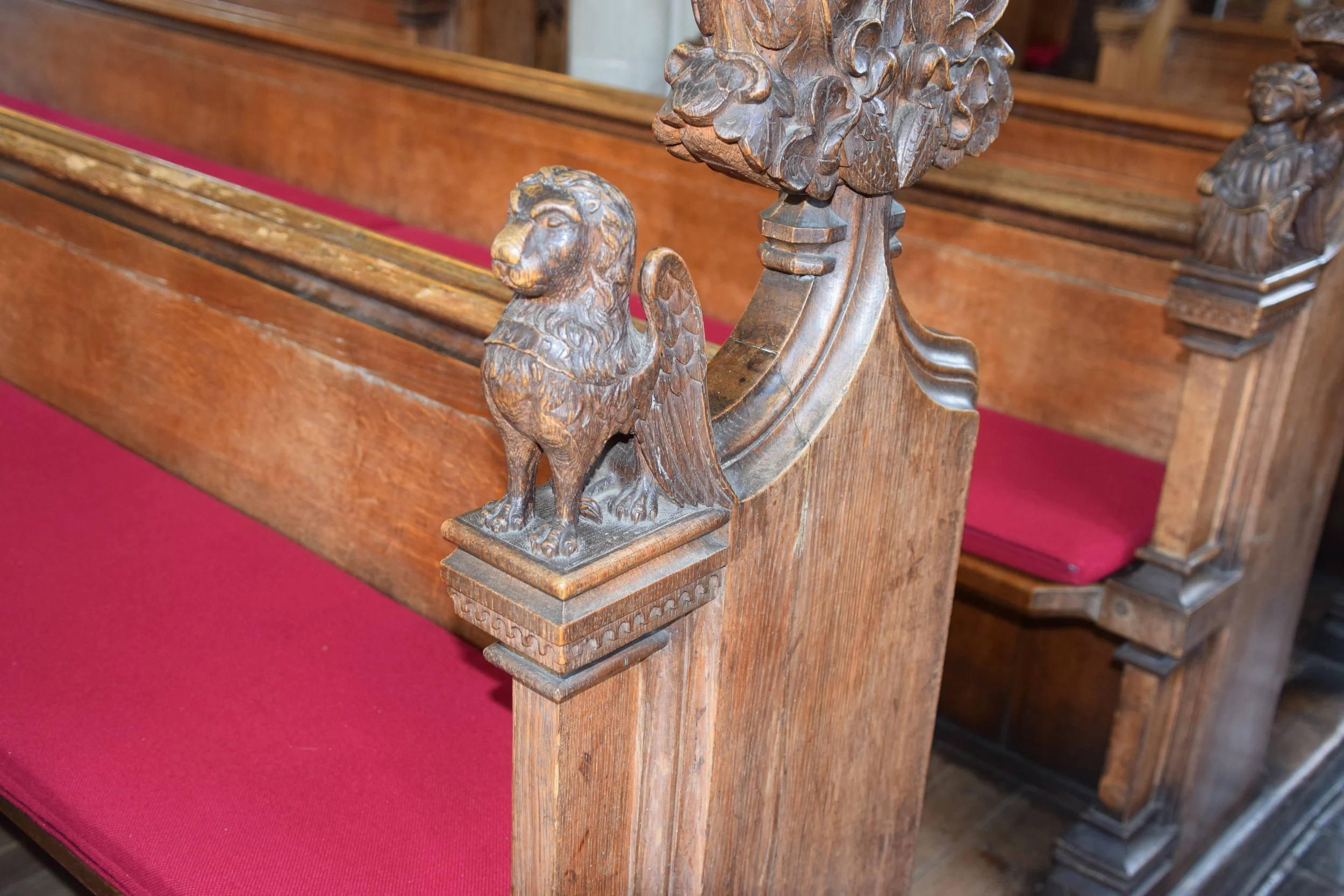 Carved wooden eagle ornament on a historic church pew with red velvet cushions