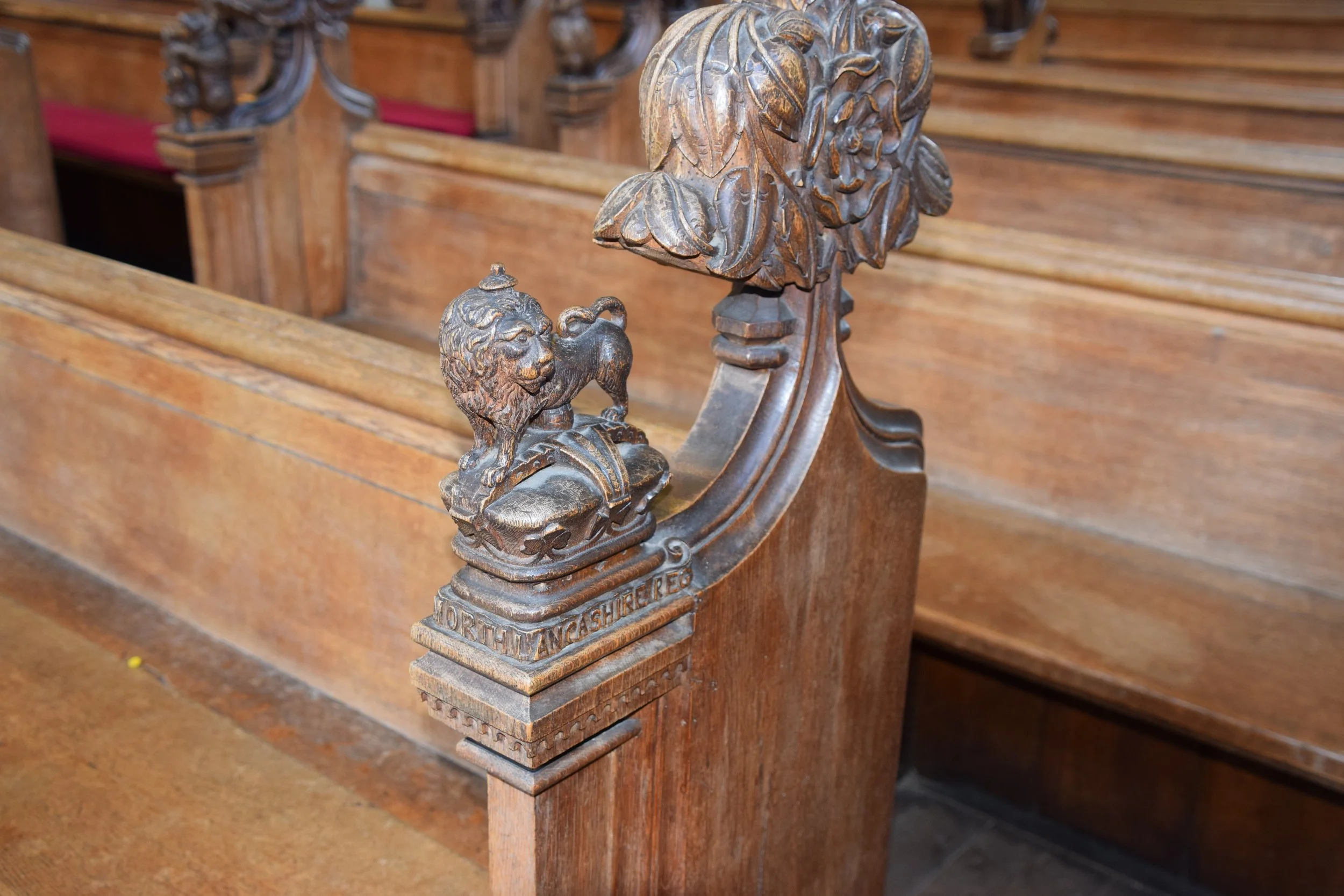 Ornate carved wooden church pew end with lion and foliage decorations