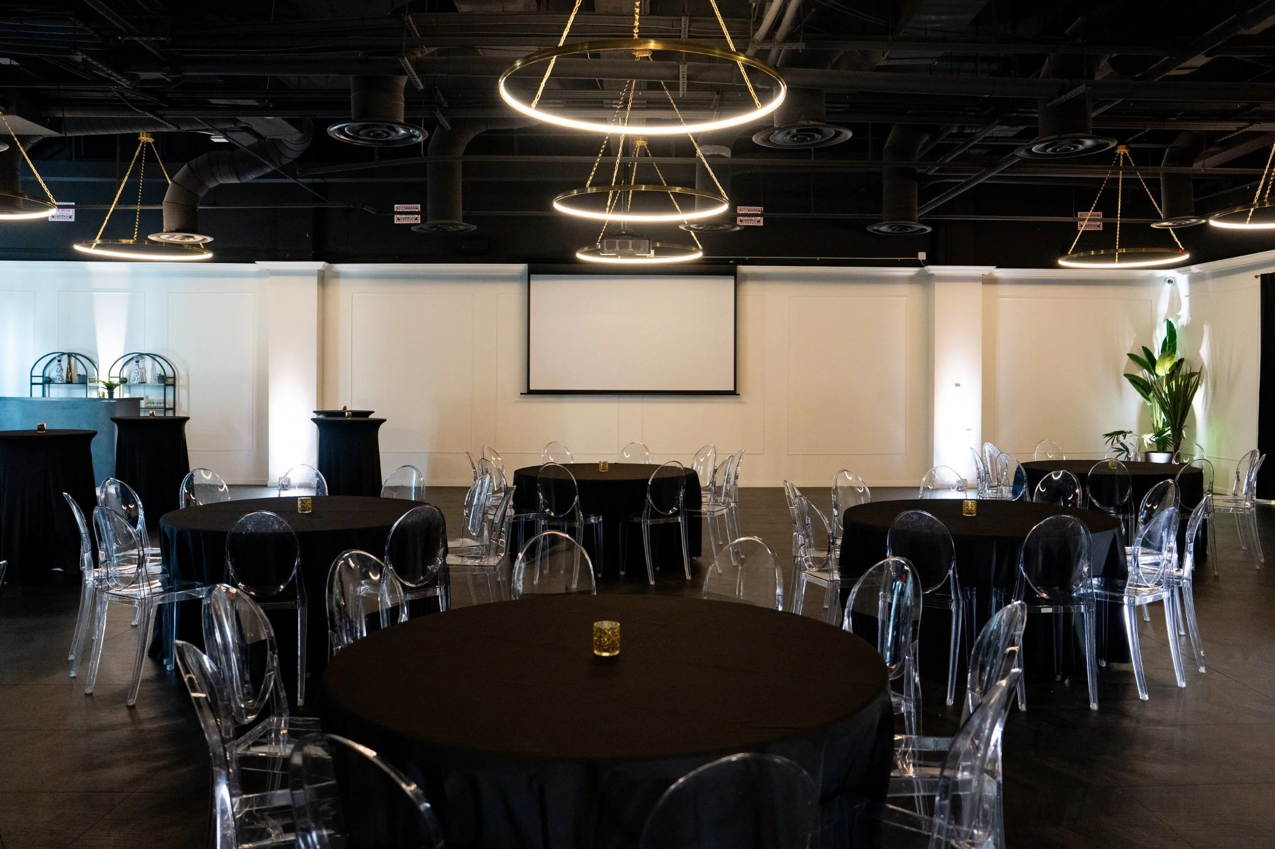 Corporate event setup at The Agave Room with round tables, ghost chairs and projector screen near the Orange County Convention Center