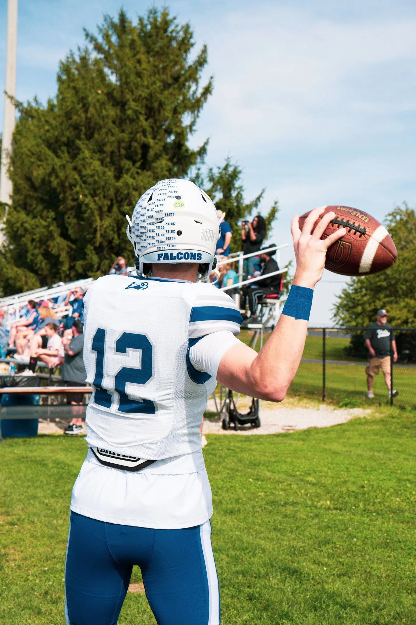 Football player wearing a white Falcons jersey and helmet holding a football on a sunny field