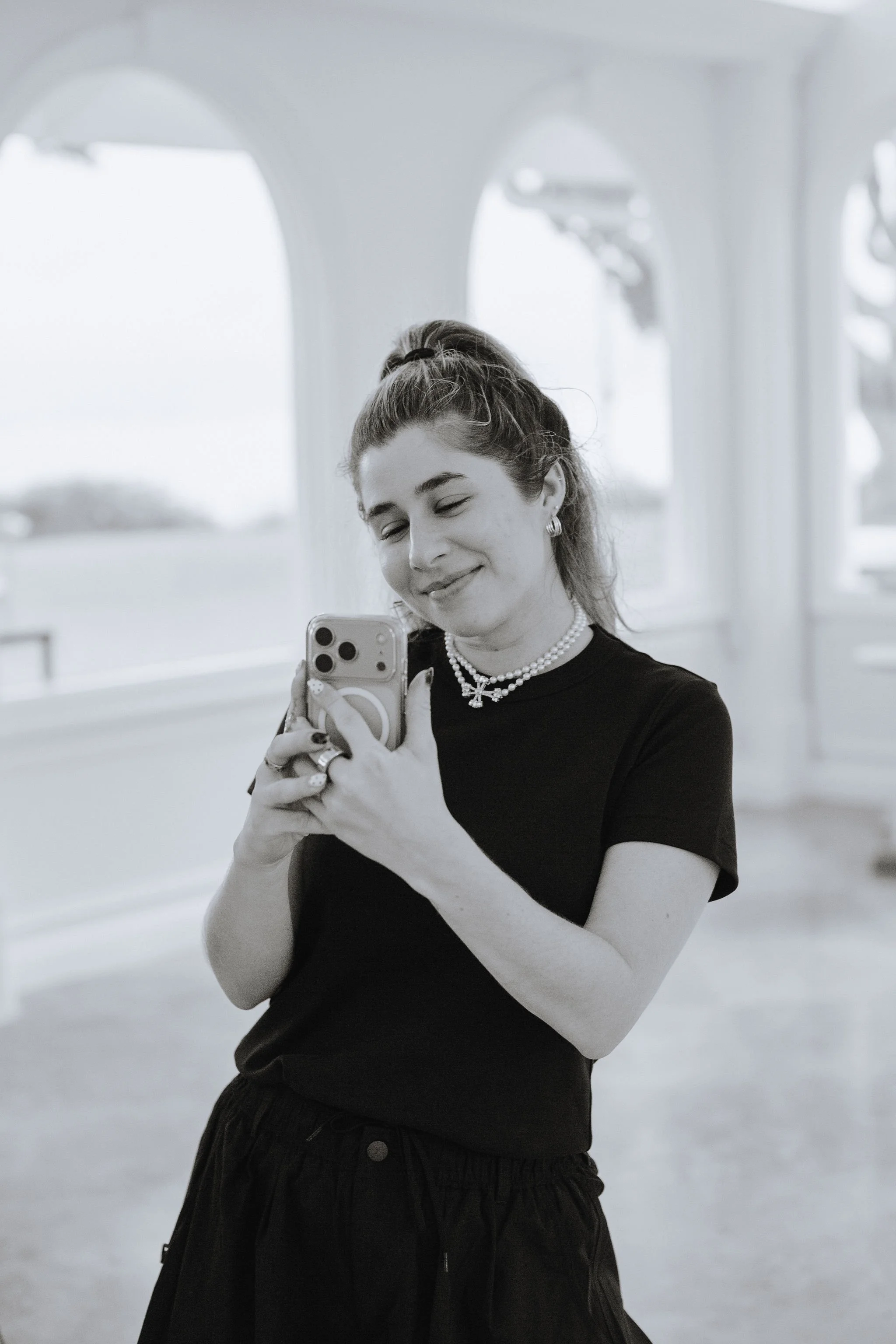 Woman smiling while taking a mirror selfie with a smartphone indoors