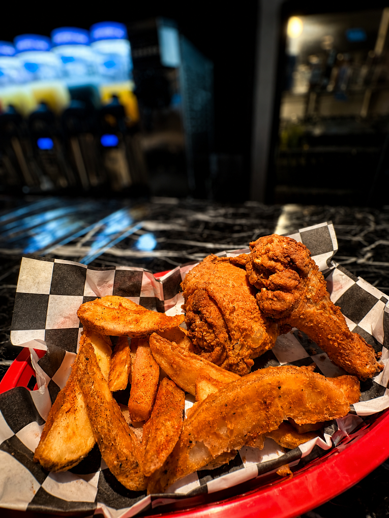 Basket of crispy fried chicken wings and tenders on black-and-white checkered paper