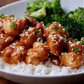 Glazed sesame chicken with green onions and broccoli served over white rice
