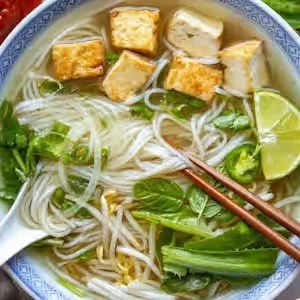 Vietnamese tofu and rice noodle soup with herbs, bean sprouts, lime, and chopsticks