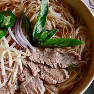 Vietnamese beef pho with rice noodles, sliced beef, bean sprouts, red onion, jalapeño, and fresh herbs