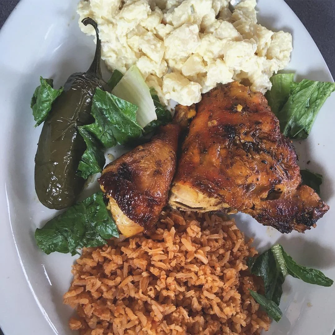 Plate of grilled chicken with rice, potato salad, lettuce, and a roasted green pepper