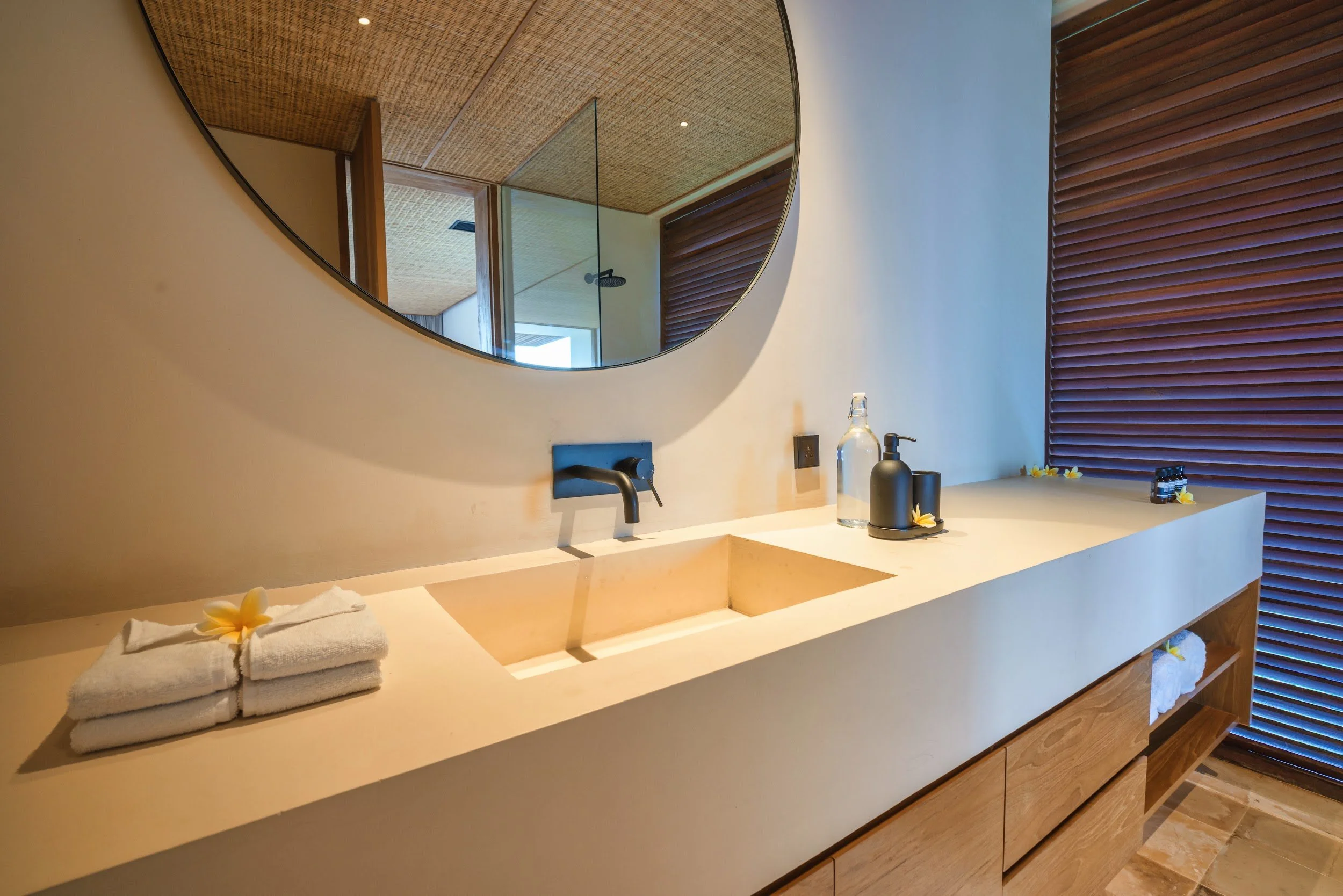Primary suite ensuite bathroom with round mirror at Villa Kai Lani