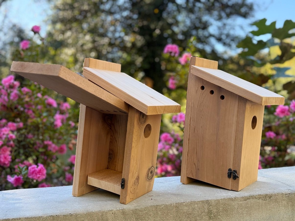 Two Eastern Bluebird Nestboxes outdoors, one with its front panel open and one showing ventilation holes on the side