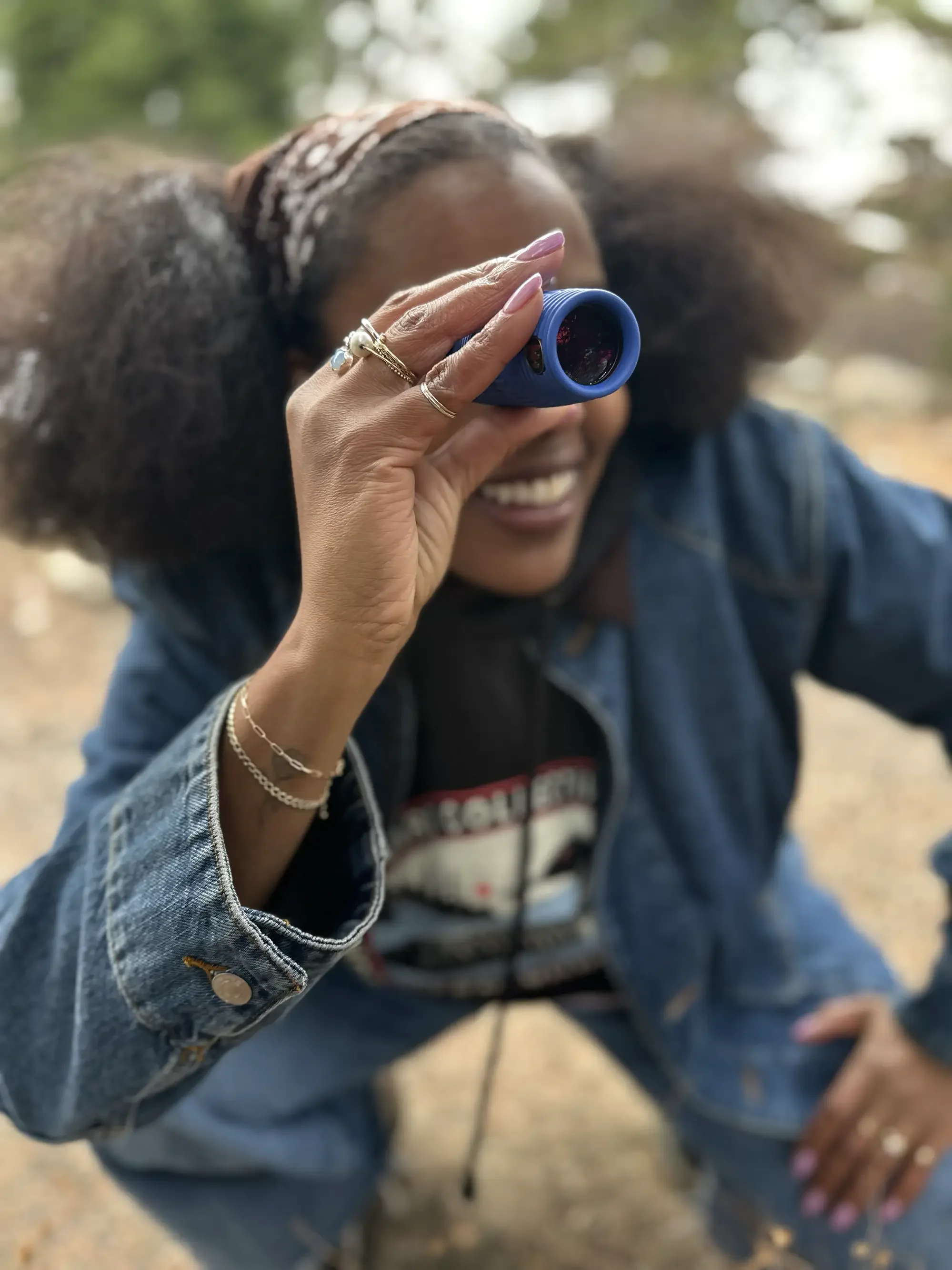 Smiling woman holding blue binoculars outdoors
