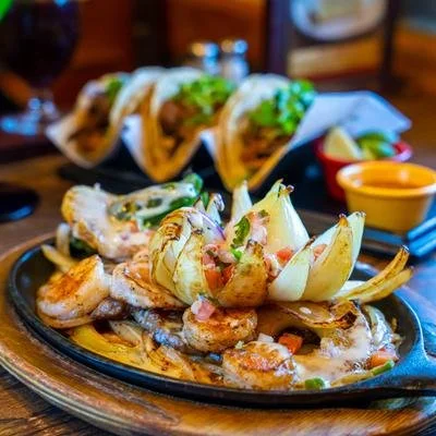 Grilled shrimp and seafood platter with tacos, vegetables, and dipping sauce