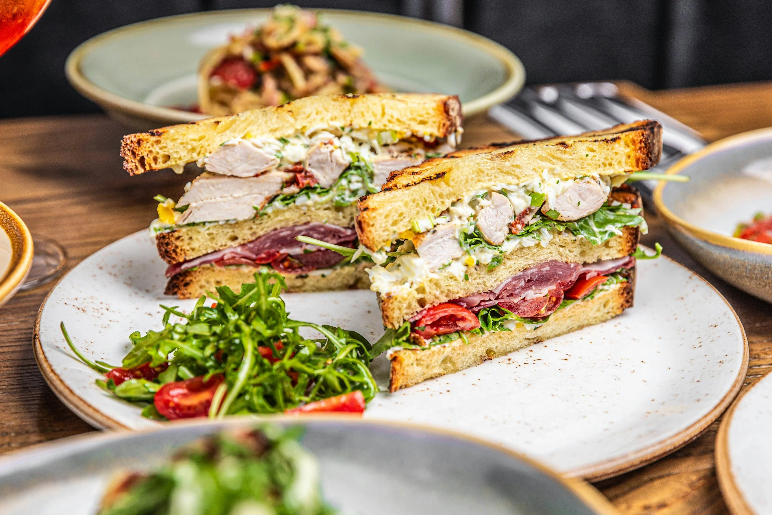 Grilled chicken and deli meat sandwiches with creamy slaw, lettuce, and tomato, served with arugula salad.