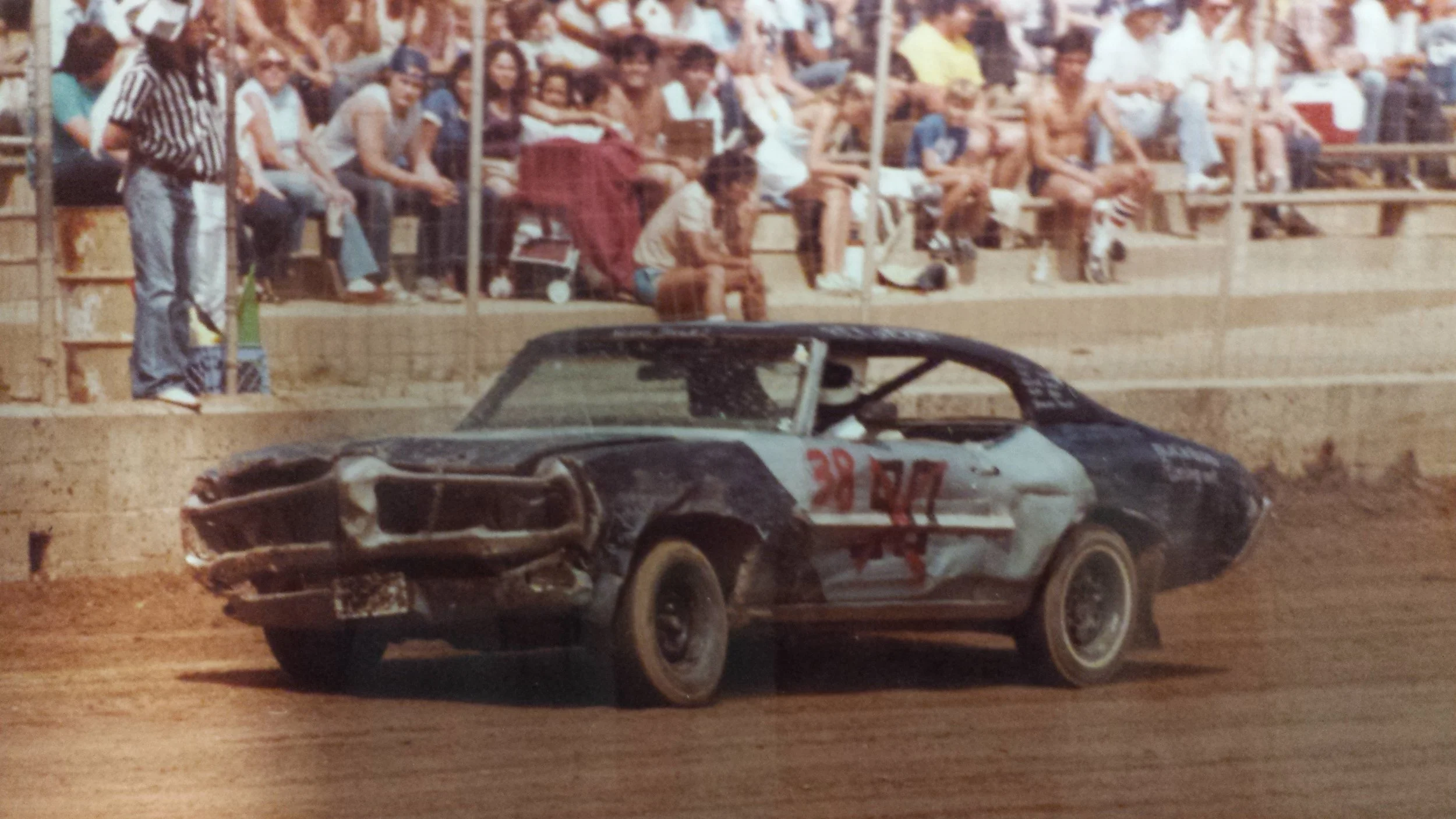 Vintage stock car race car number 39 on a dirt track with spectators in the stands