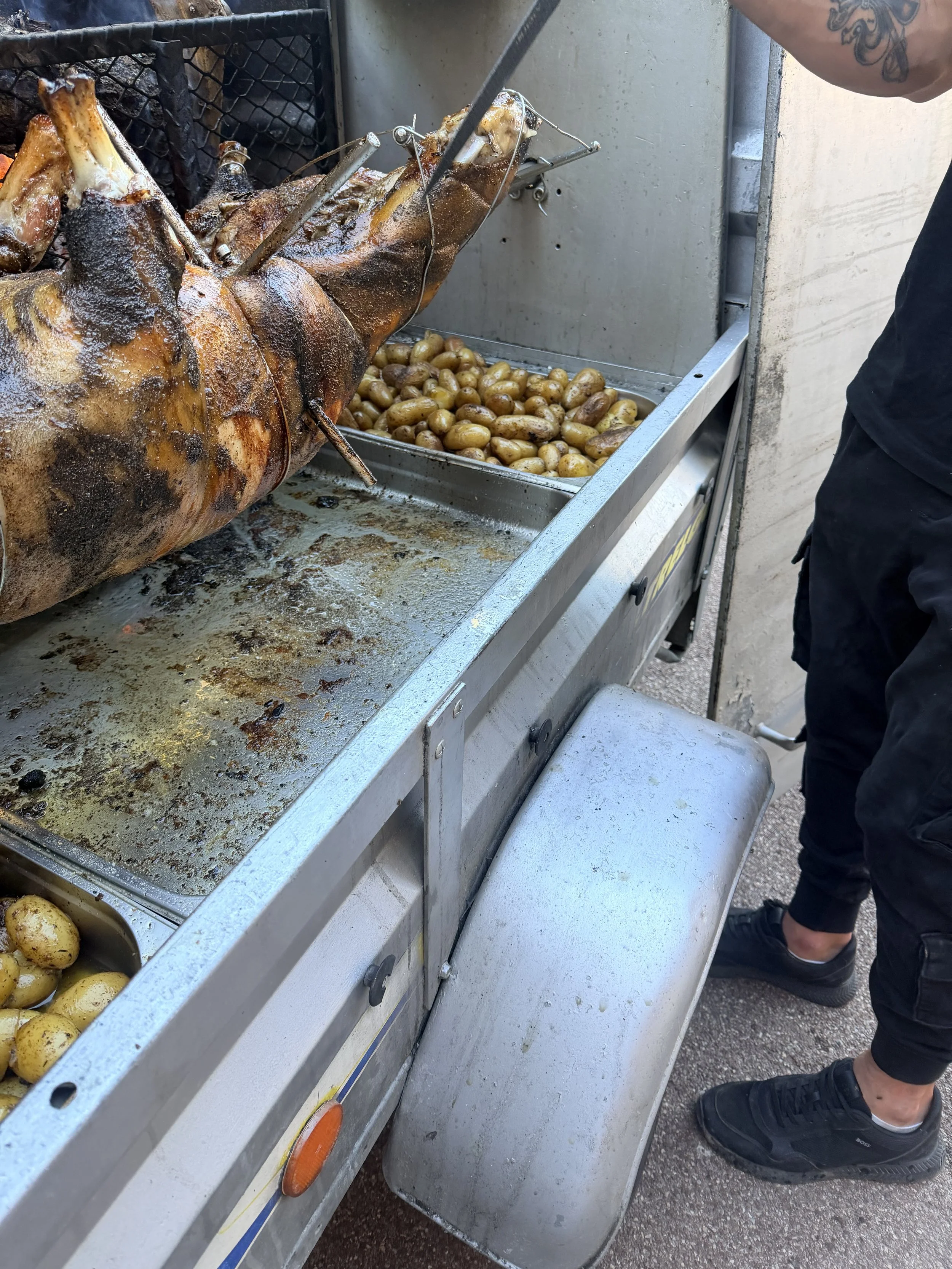 cochon de lait rôti à la broche avec pommes de terre, sur un barbecue de rue.