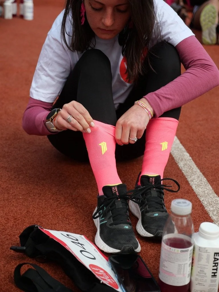 A runner pulling on pink compression socks before the start