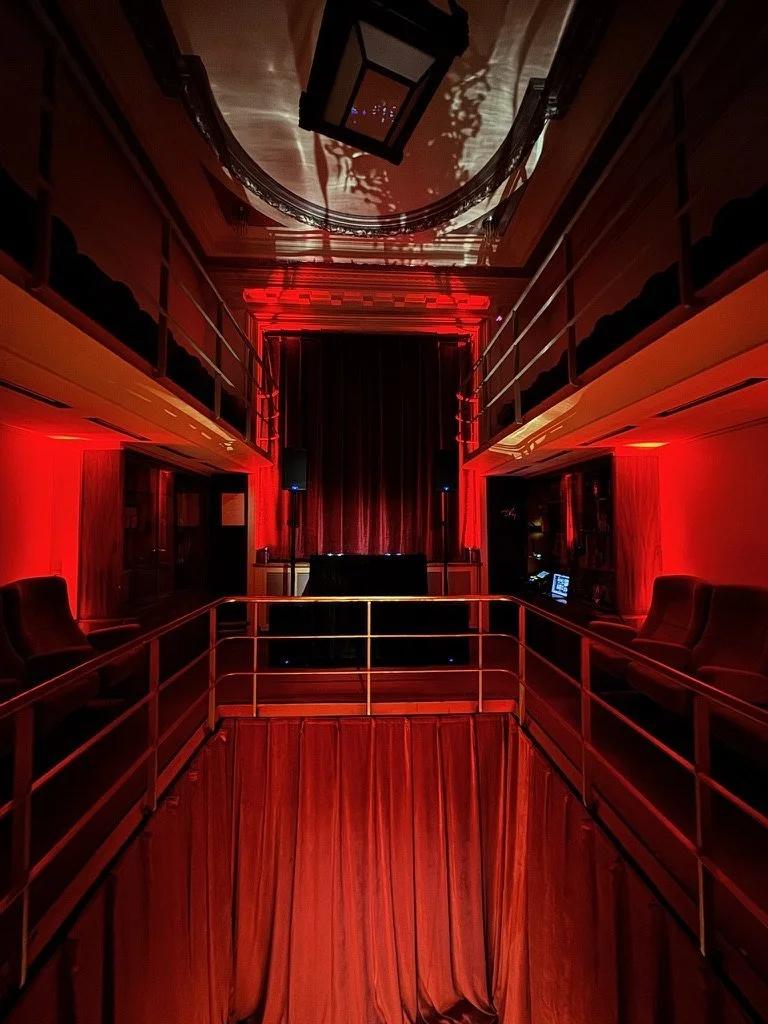 The DJ booth on a red-lit landing between balconies