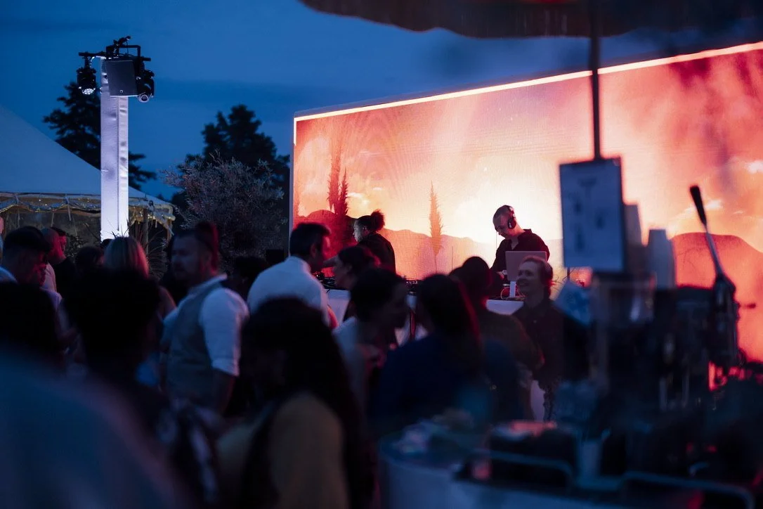 A DJ in front of a glowing screen as night falls