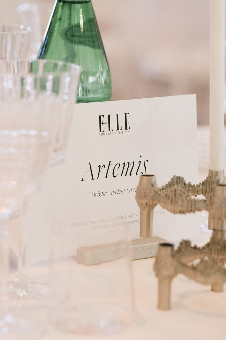 A table card reading Artemis beside a sculptural candleholder