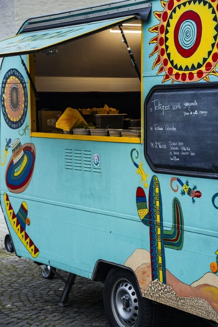 A hand-painted turquoise taco truck with its chalkboard menu