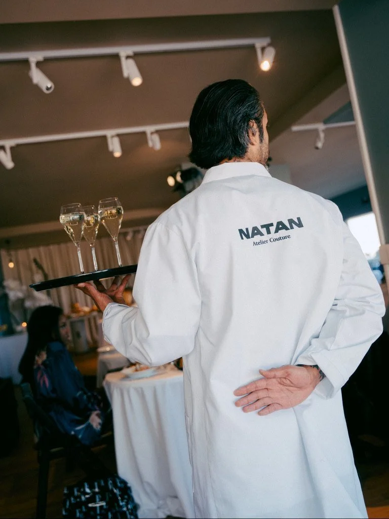 A waiter in a NATAN Atelier Couture coat carrying champagne